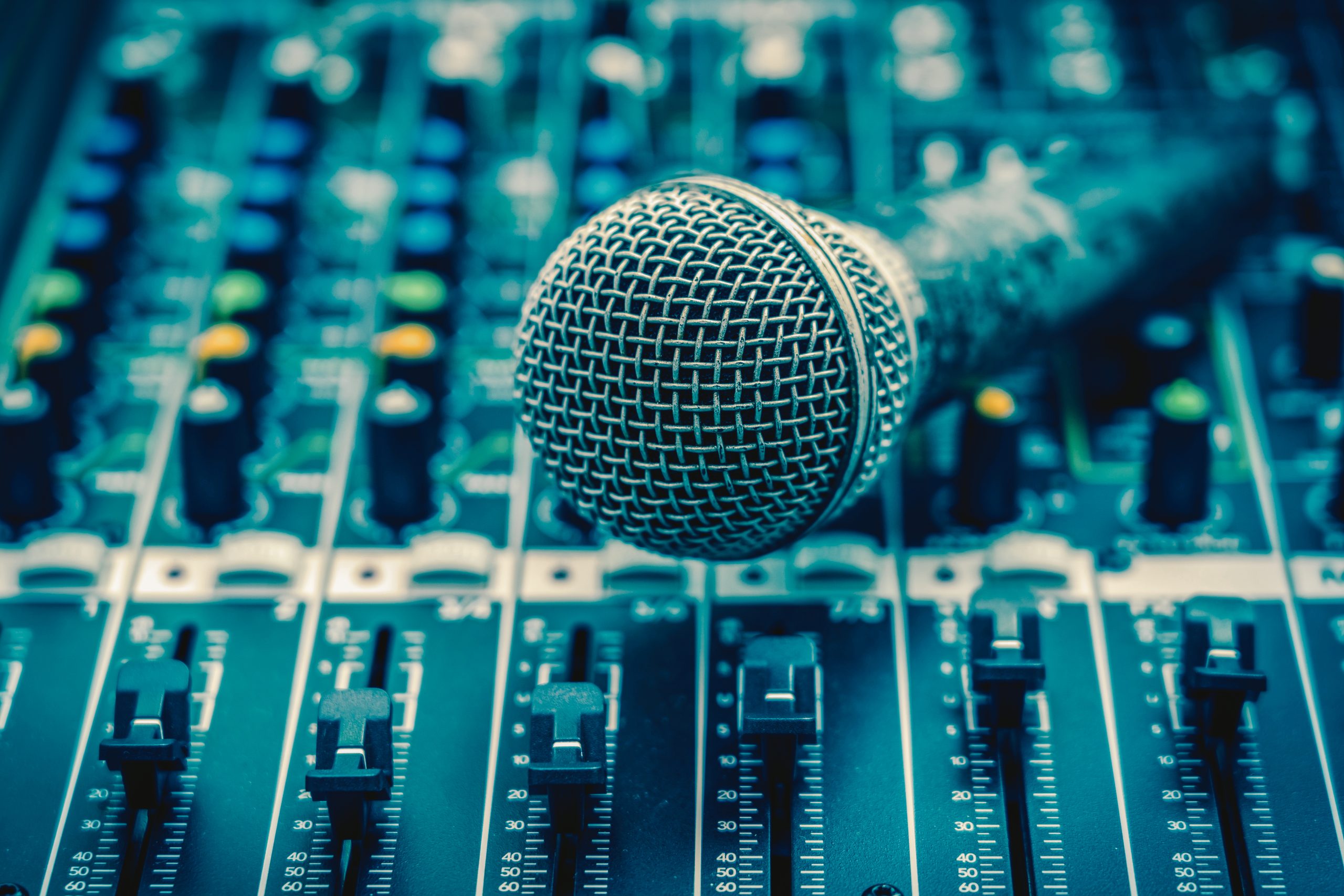 Close-up of a microphone resting on an audio mixing console.